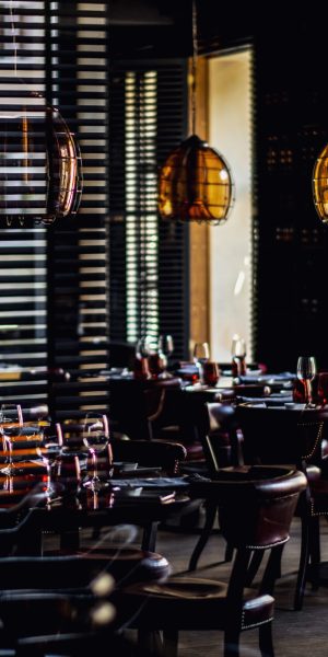 Restorano interjeras su apvaliais stalais, taurėmis su raudonu gėrimu ir gintaro spalvos